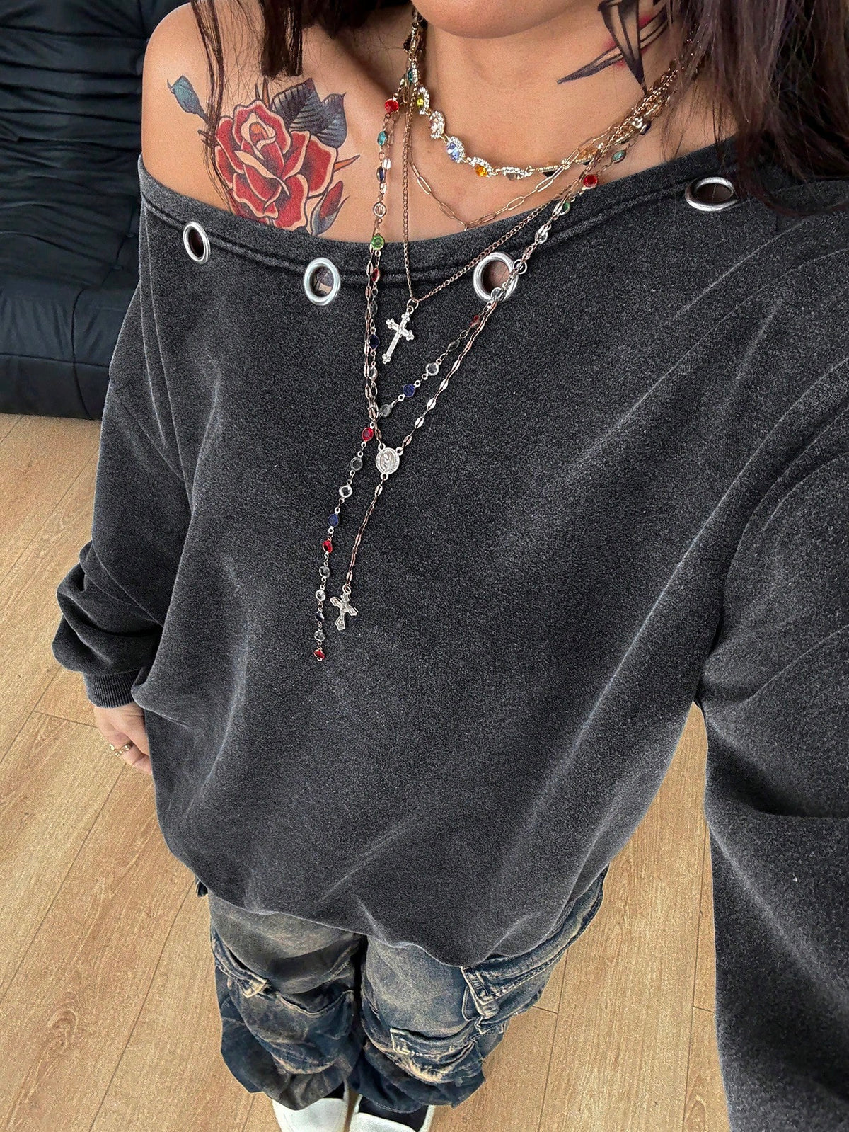 Women's oversized dark grey long sleeve sweatshirt featuring an asymmetrical boat neckline with grommet eyelet details and drop shoulders.