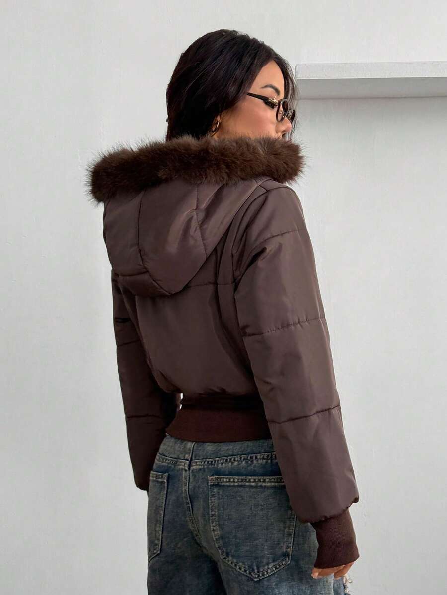 Women's brown cropped puffer jacket featuring a faux fur trimmed hood, front zipper, and ribbed hem.