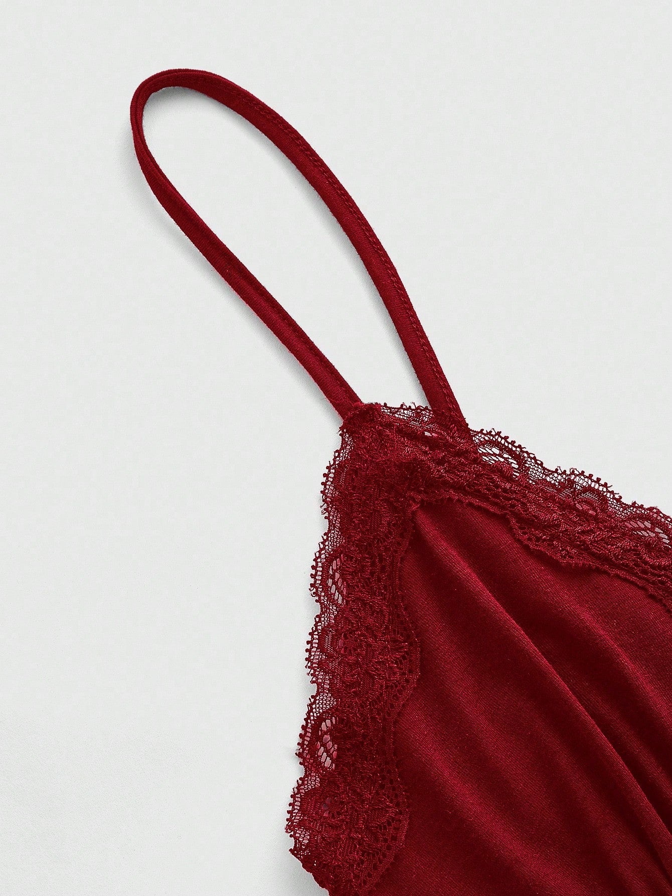 Women's spaghetti strap camisole with contrast lace patchwork, slim fit silhouette, plain design, and flared hem.