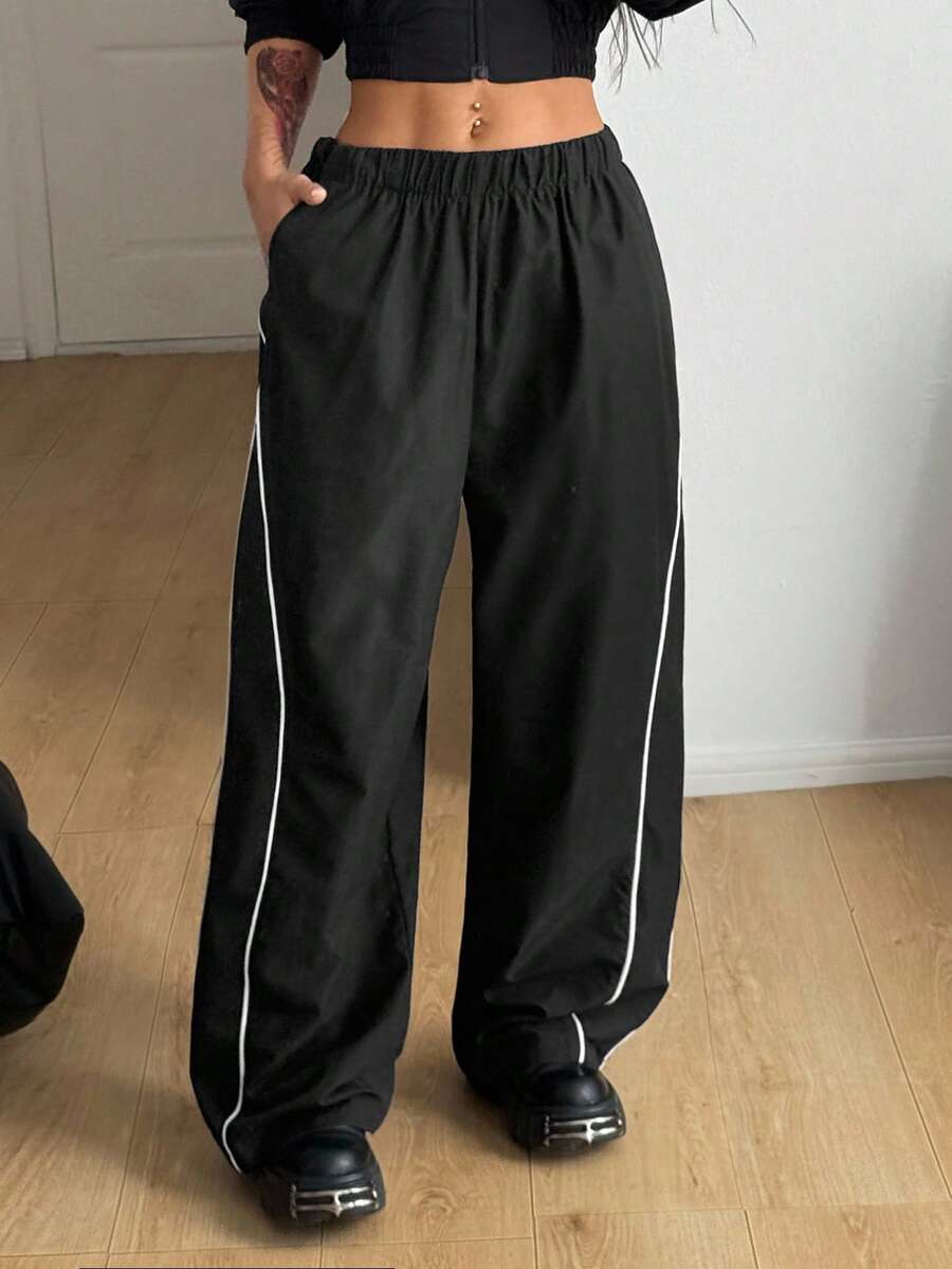 Women's black loose fit wide leg pants featuring an elastic waistband and side pockets with contrast binding.