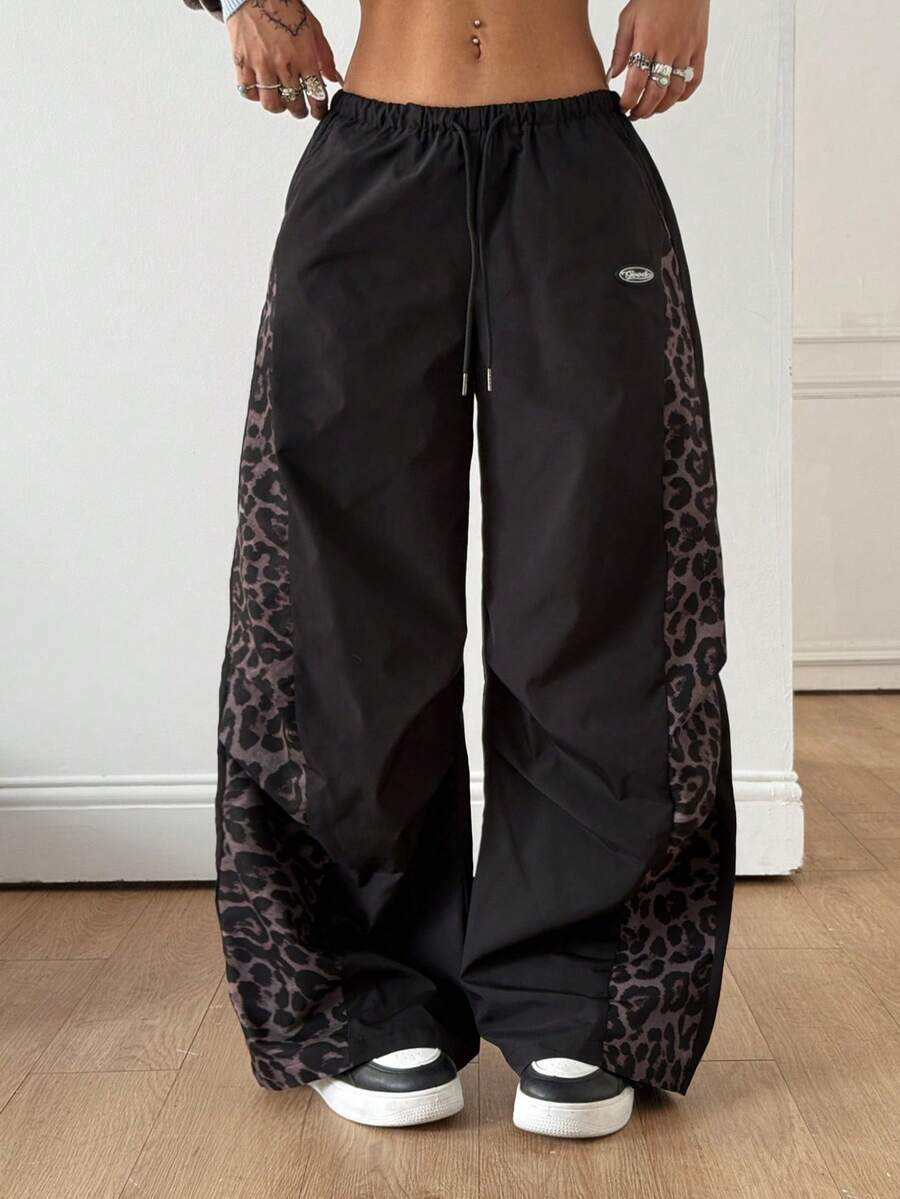 Women's black baggy jogger pants with an adjustable drawstring waist and colorblock polka dot geometric pattern.