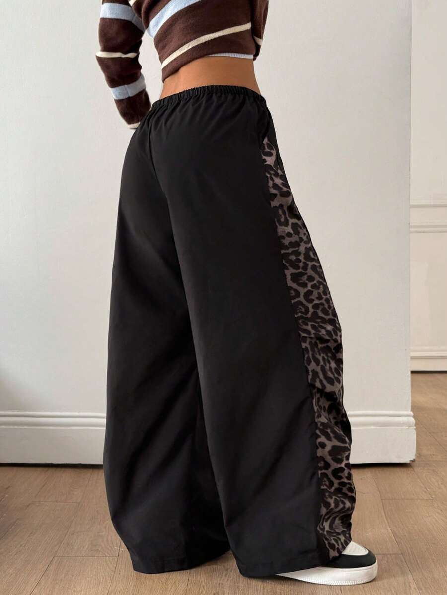 Women's black baggy jogger pants with an adjustable drawstring waist and colorblock polka dot geometric pattern.