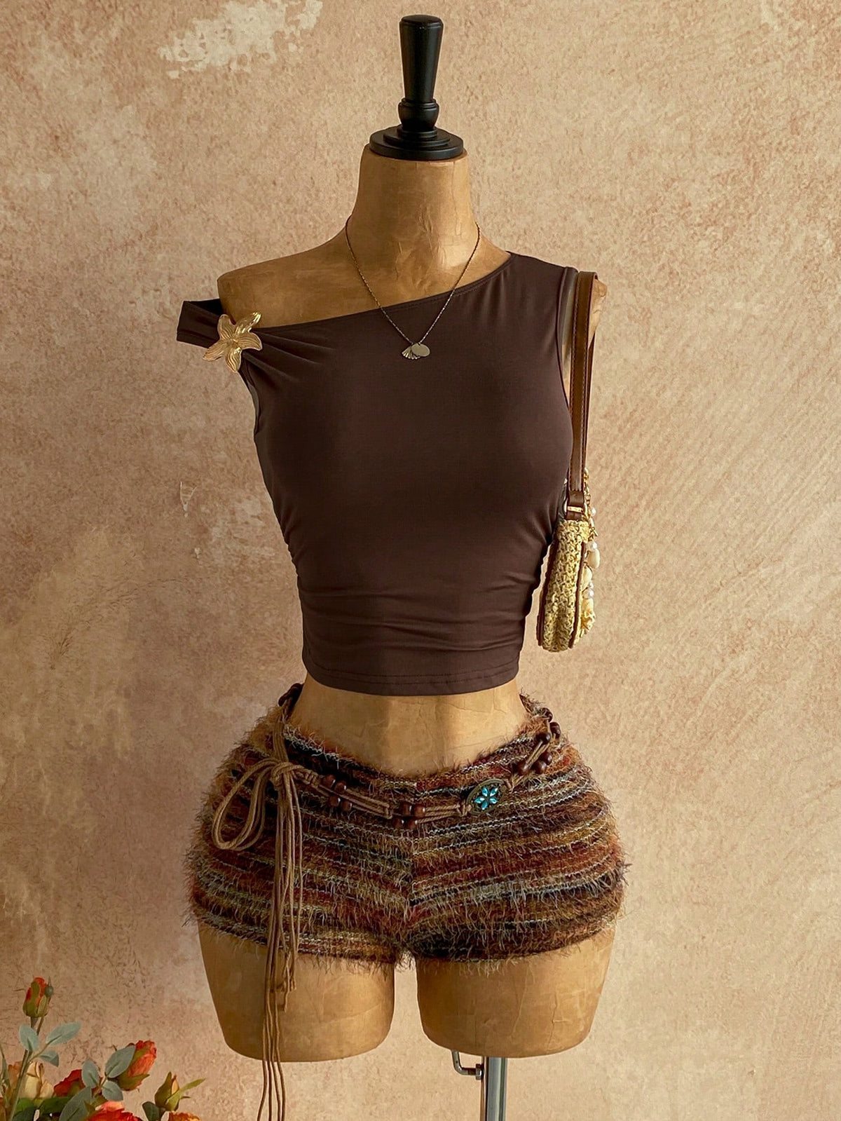 Women's black fuzzy knit two-piece set with an asymmetrical crop camisole top featuring ruched detail and cutout back, paired with matching mini shorts.