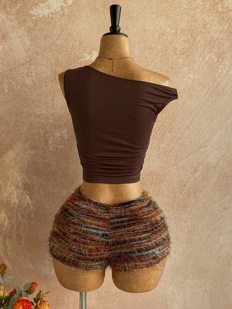 Women's black fuzzy knit two-piece set with an asymmetrical crop camisole top featuring ruched detail and cutout back, paired with matching mini shorts.