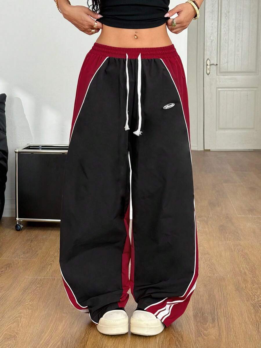 Women's plus size loose straight leg pants featuring a black and white color block design with side stripes and an elastic drawstring waist.