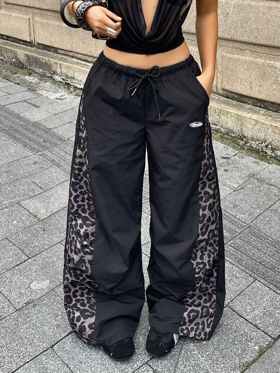 Women's black baggy jogger pants with an adjustable drawstring waist and colorblock polka dot geometric pattern.