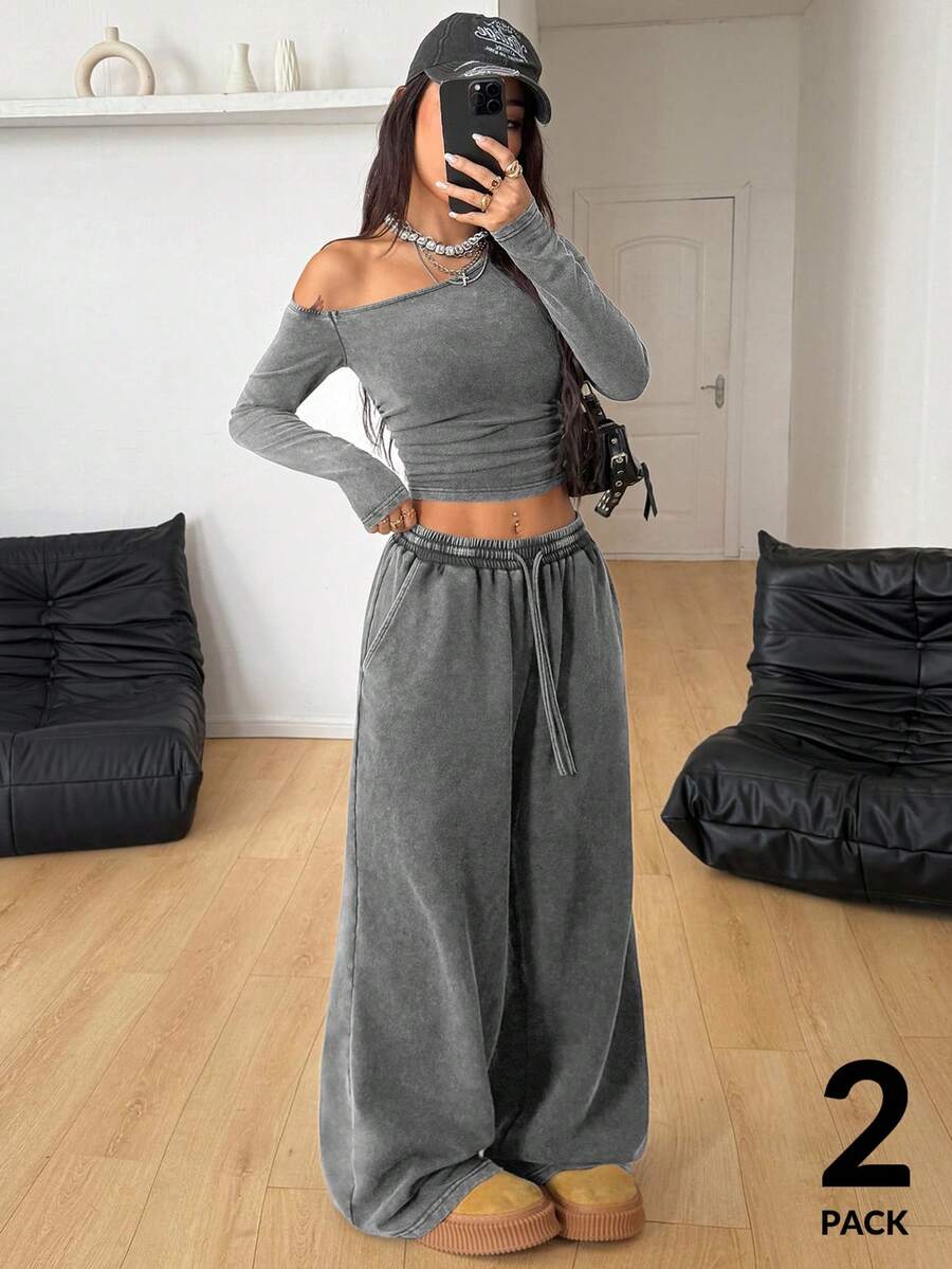Women's two-piece knit lounge set featuring a black long sleeve asymmetrical crop top and matching high-waisted wide leg sweatpants.