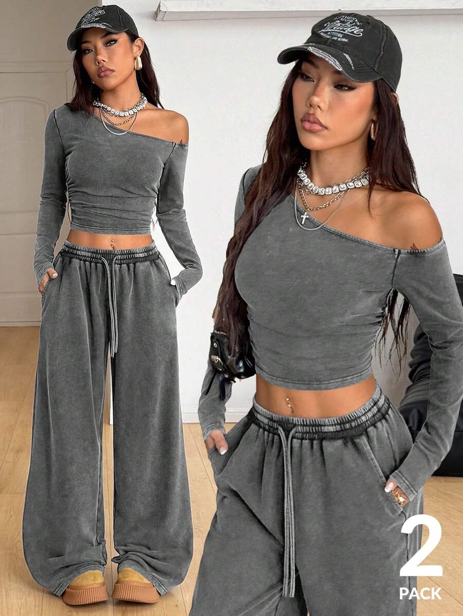 Women's two-piece knit lounge set featuring a black long sleeve asymmetrical crop top and matching high-waisted wide leg sweatpants.