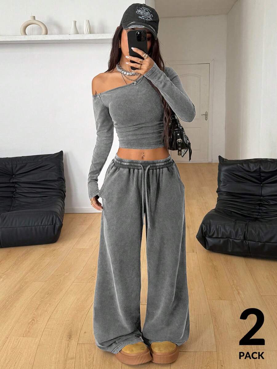 Women's two-piece knit lounge set featuring a black long sleeve asymmetrical crop top and matching high-waisted wide leg sweatpants.