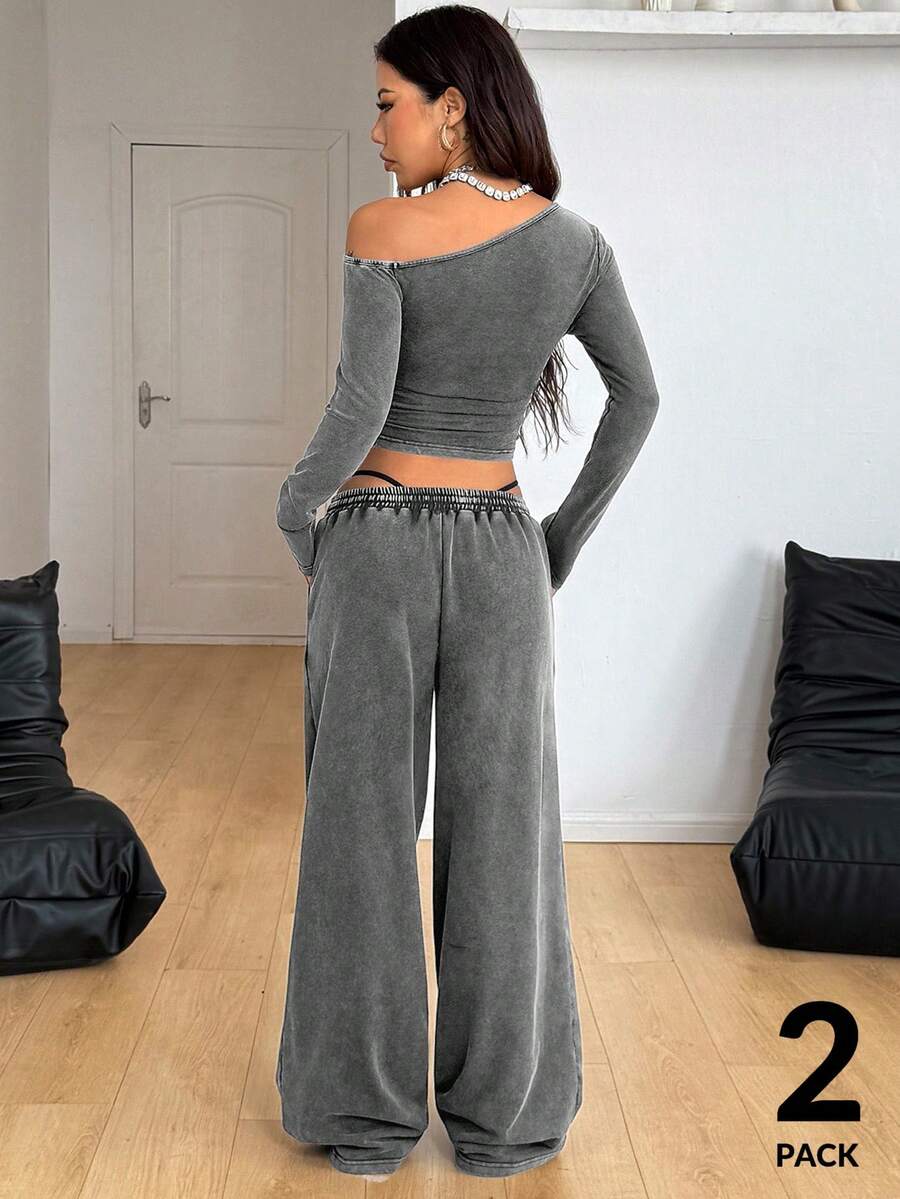 Women's two-piece knit lounge set featuring a black long sleeve asymmetrical crop top and matching high-waisted wide leg sweatpants.