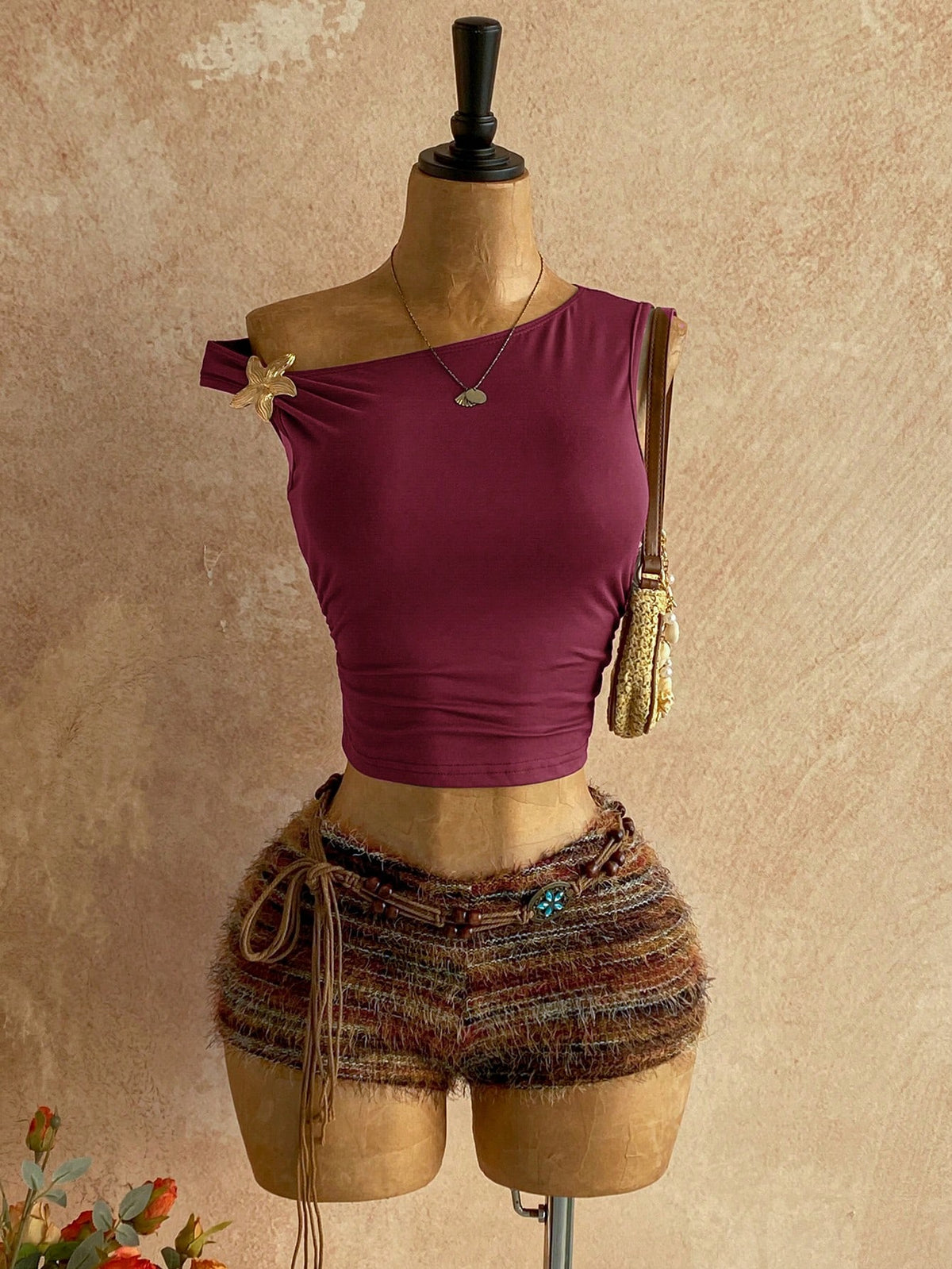 Women's black fuzzy knit two-piece set with an asymmetrical crop camisole top featuring ruched detail and cutout back, paired with matching mini shorts.