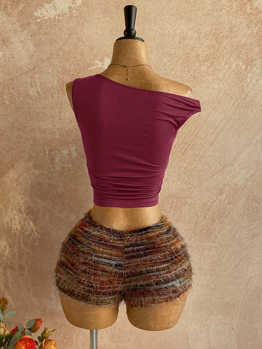 Women's black fuzzy knit two-piece set with an asymmetrical crop camisole top featuring ruched detail and cutout back, paired with matching mini shorts.