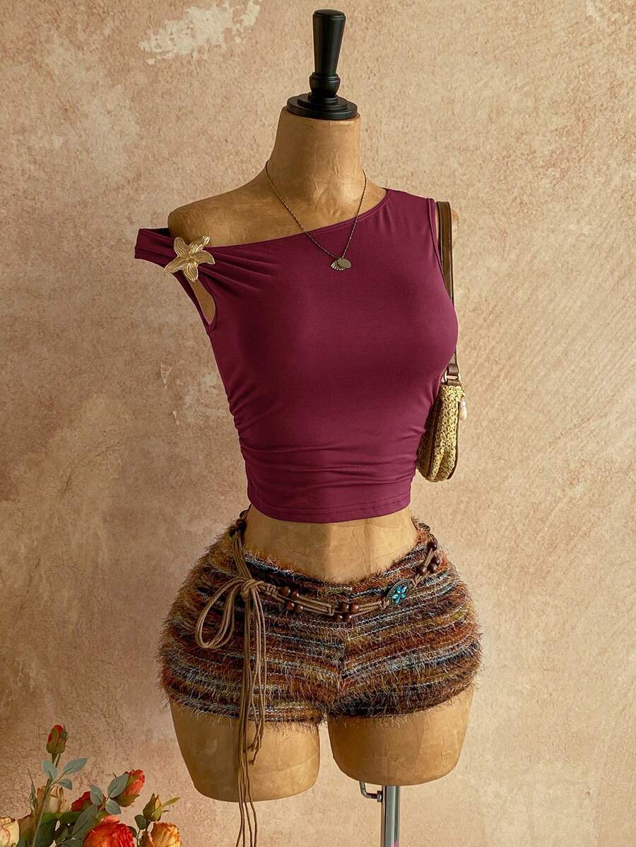 Women's black fuzzy knit two-piece set with an asymmetrical crop camisole top featuring ruched detail and cutout back, paired with matching mini shorts.
