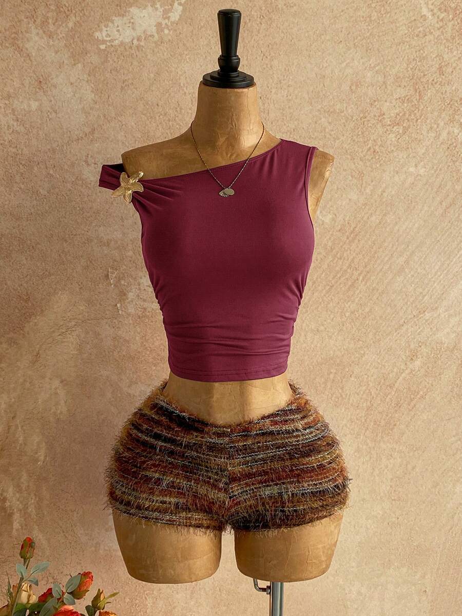 Women's black fuzzy knit two-piece set with an asymmetrical crop camisole top featuring ruched detail and cutout back, paired with matching mini shorts.