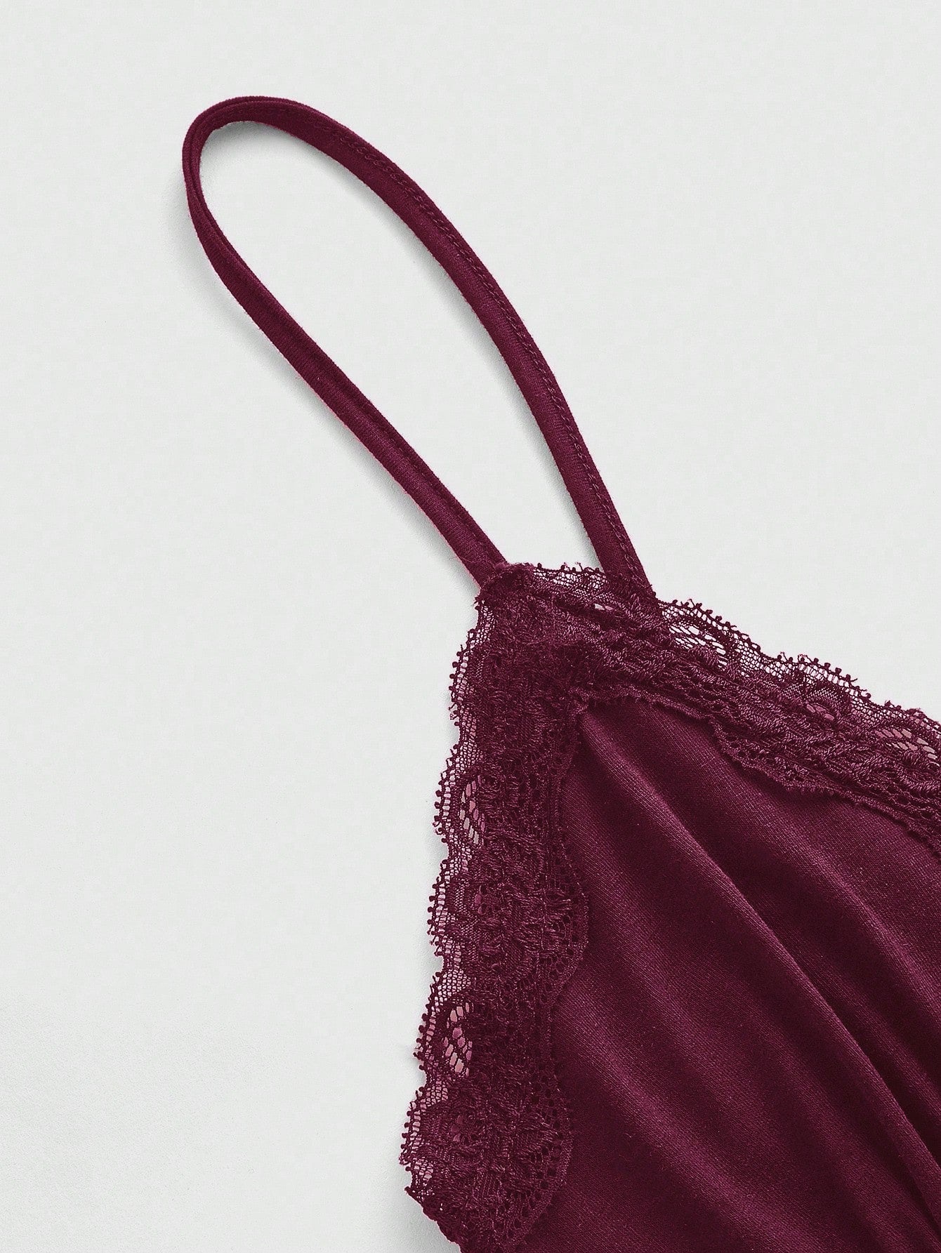 Women's spaghetti strap camisole with contrast lace patchwork, slim fit silhouette, plain design, and flared hem.