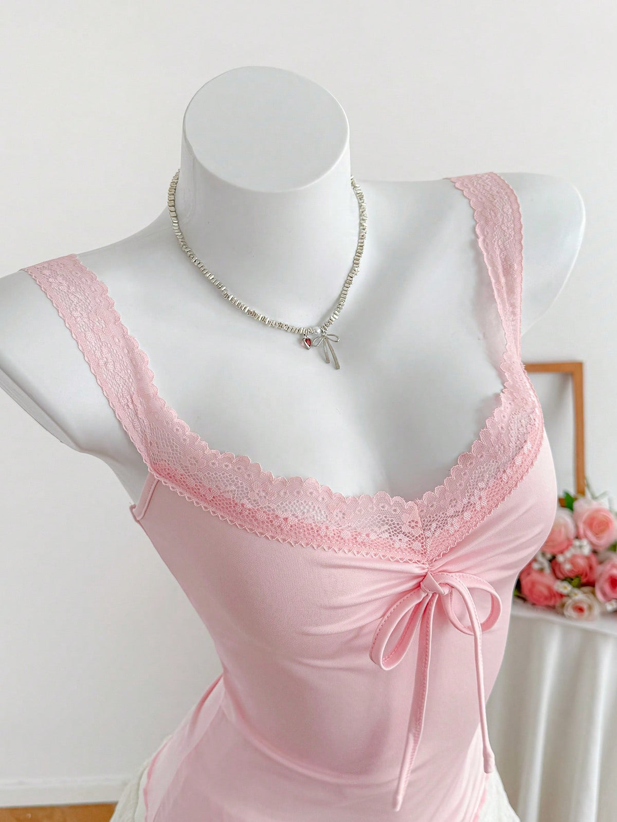 Women's slim fit casual camisole featuring wide shoulder straps, contrast lace trim, a front knot, and ruched details.