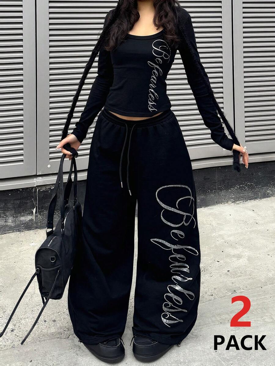 Women's black two-piece casual outfit featuring a long sleeve scoop neck letter print t-shirt and matching wide leg sweatpants made of knitted cotton blend fabric.