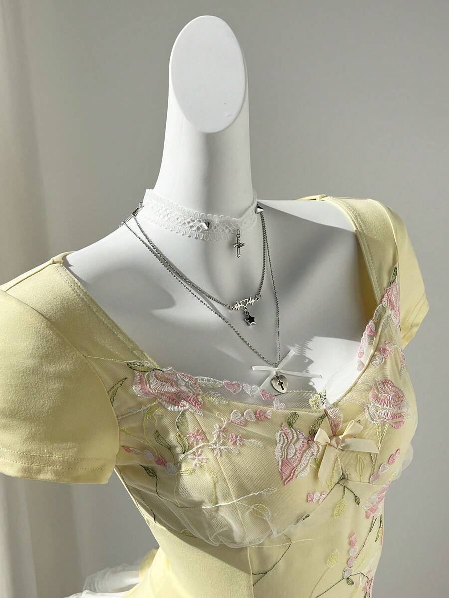 Women's pink short sleeve slim fit dress featuring a plant pattern, scoop neck, ruched appliques, and button front detail.