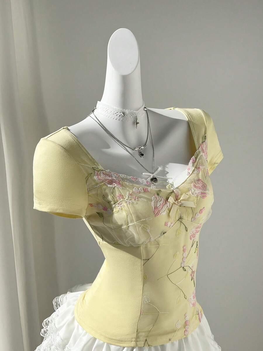 Women's pink short sleeve slim fit dress featuring a plant pattern, scoop neck, ruched appliques, and button front detail.