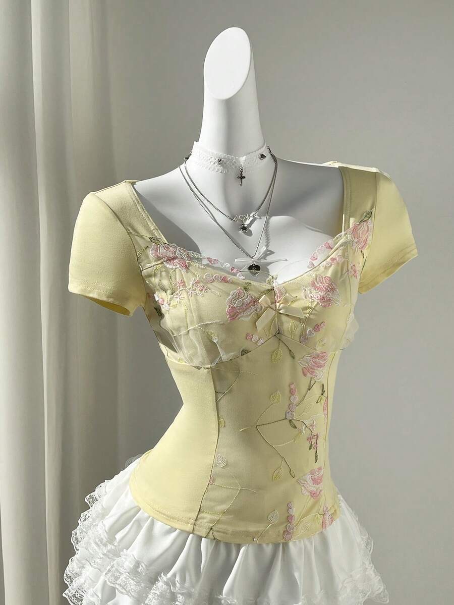 Women's pink short sleeve slim fit dress featuring a plant pattern, scoop neck, ruched appliques, and button front detail.
