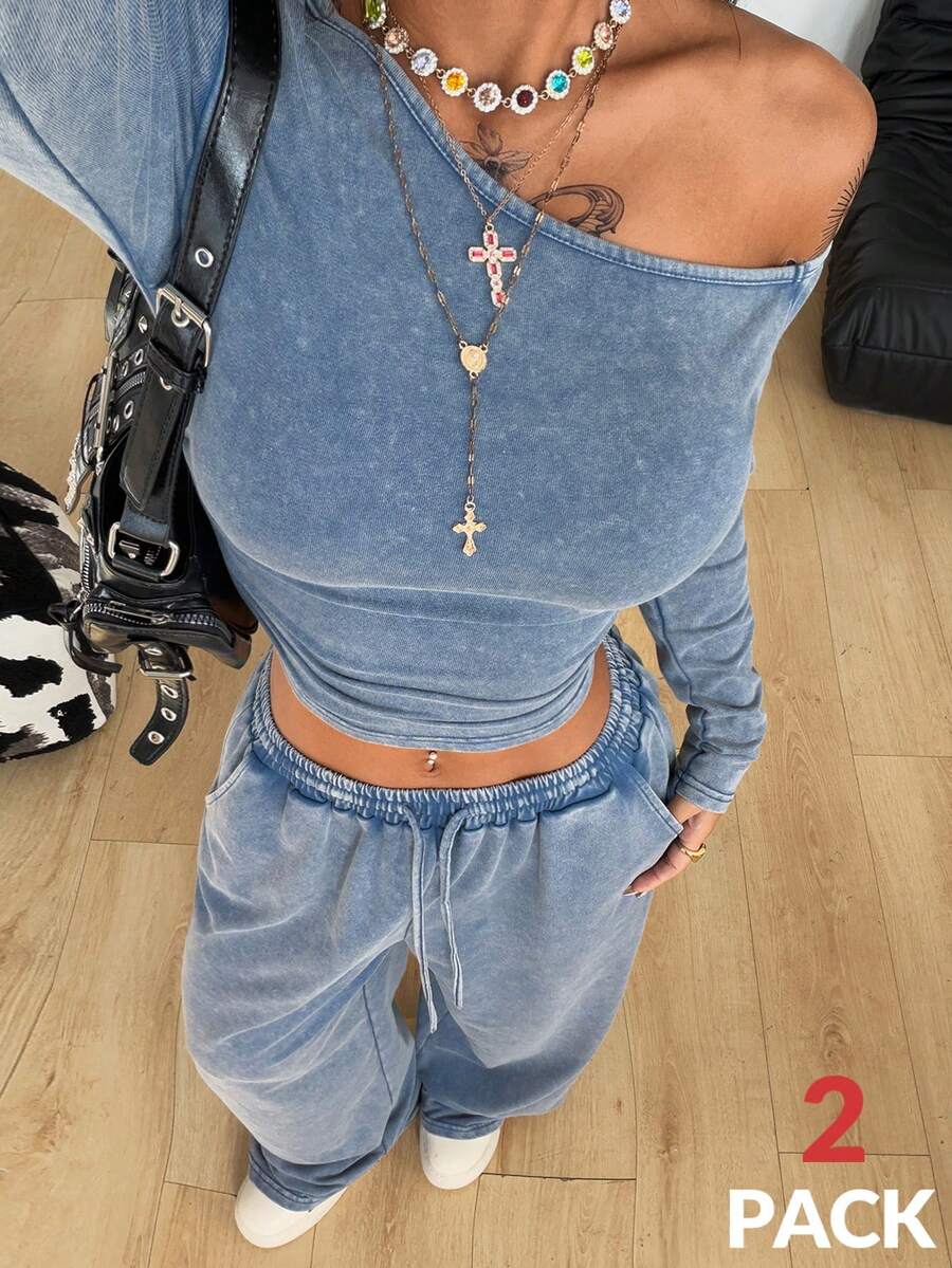 Women's two-piece knit lounge set featuring a black long sleeve asymmetrical crop top and matching high-waisted wide leg sweatpants.