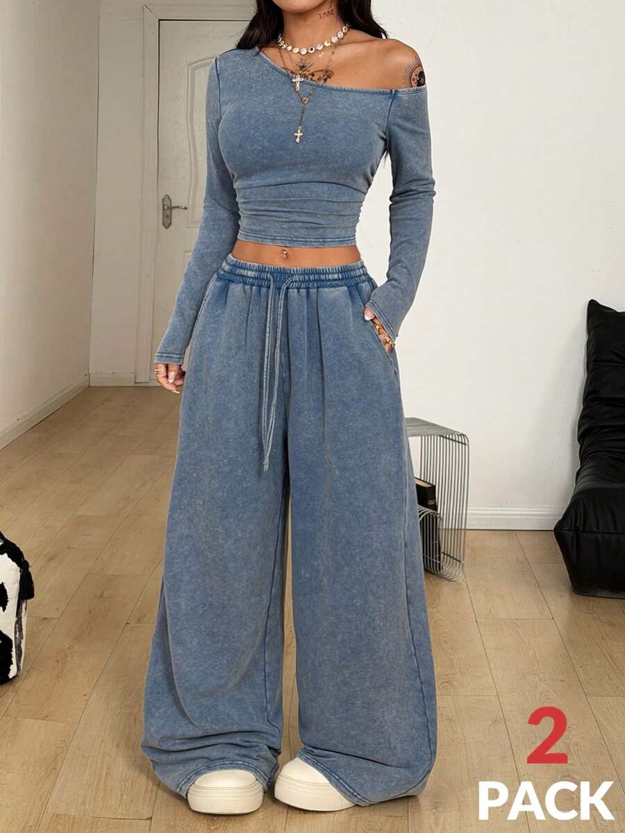 Women's two-piece knit lounge set featuring a black long sleeve asymmetrical crop top and matching high-waisted wide leg sweatpants.