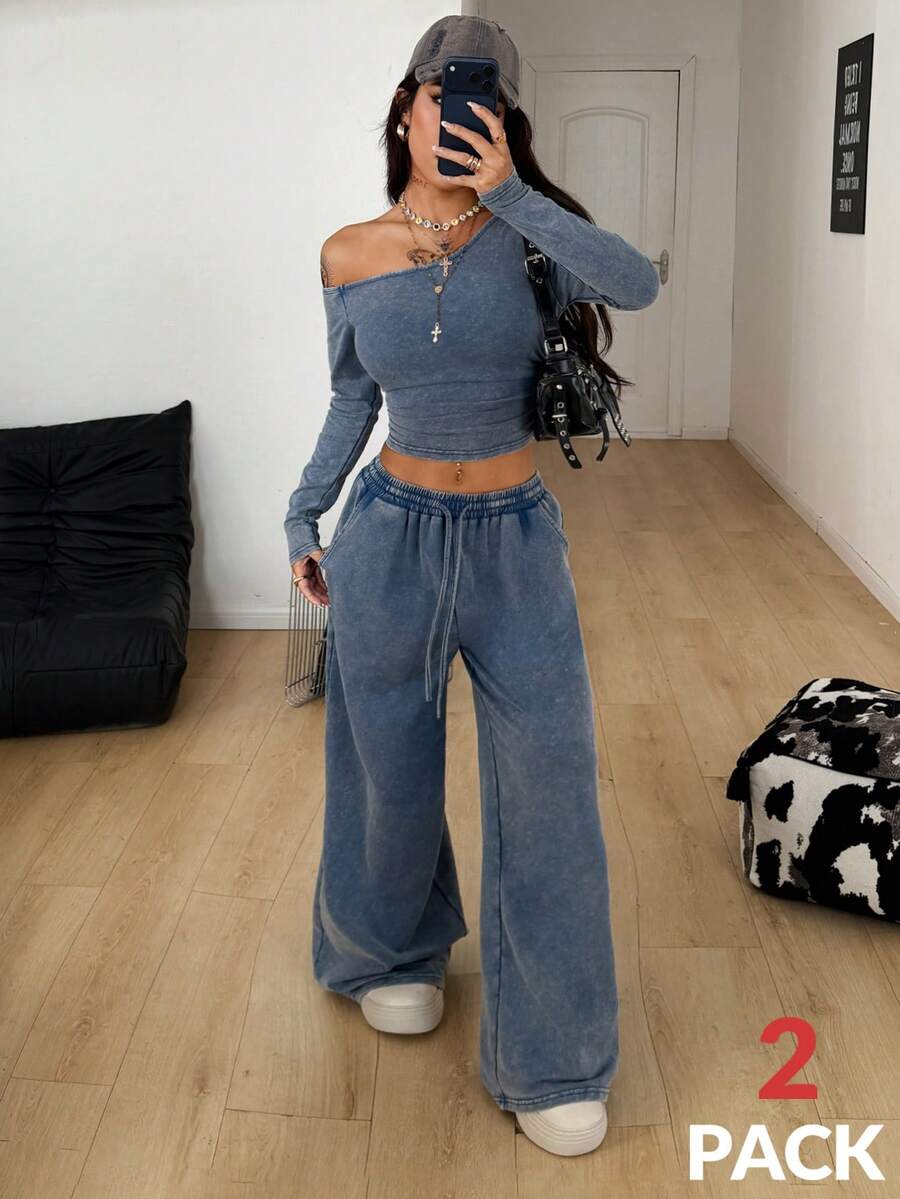 Women's two-piece knit lounge set featuring a black long sleeve asymmetrical crop top and matching high-waisted wide leg sweatpants.