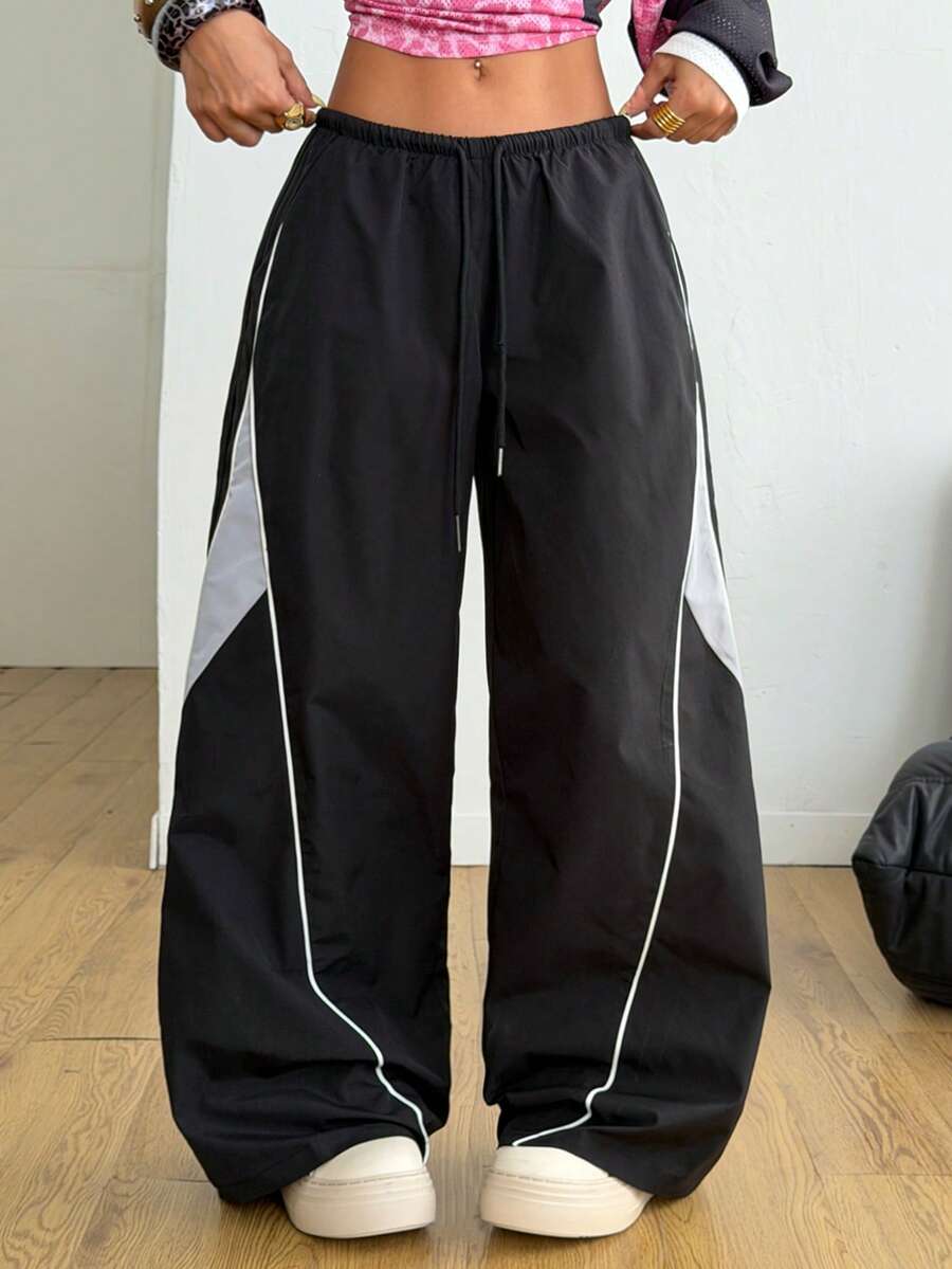 Women's wide leg parachute pants featuring an army green color-blocked design with side stripes and an adjustable drawstring waist.