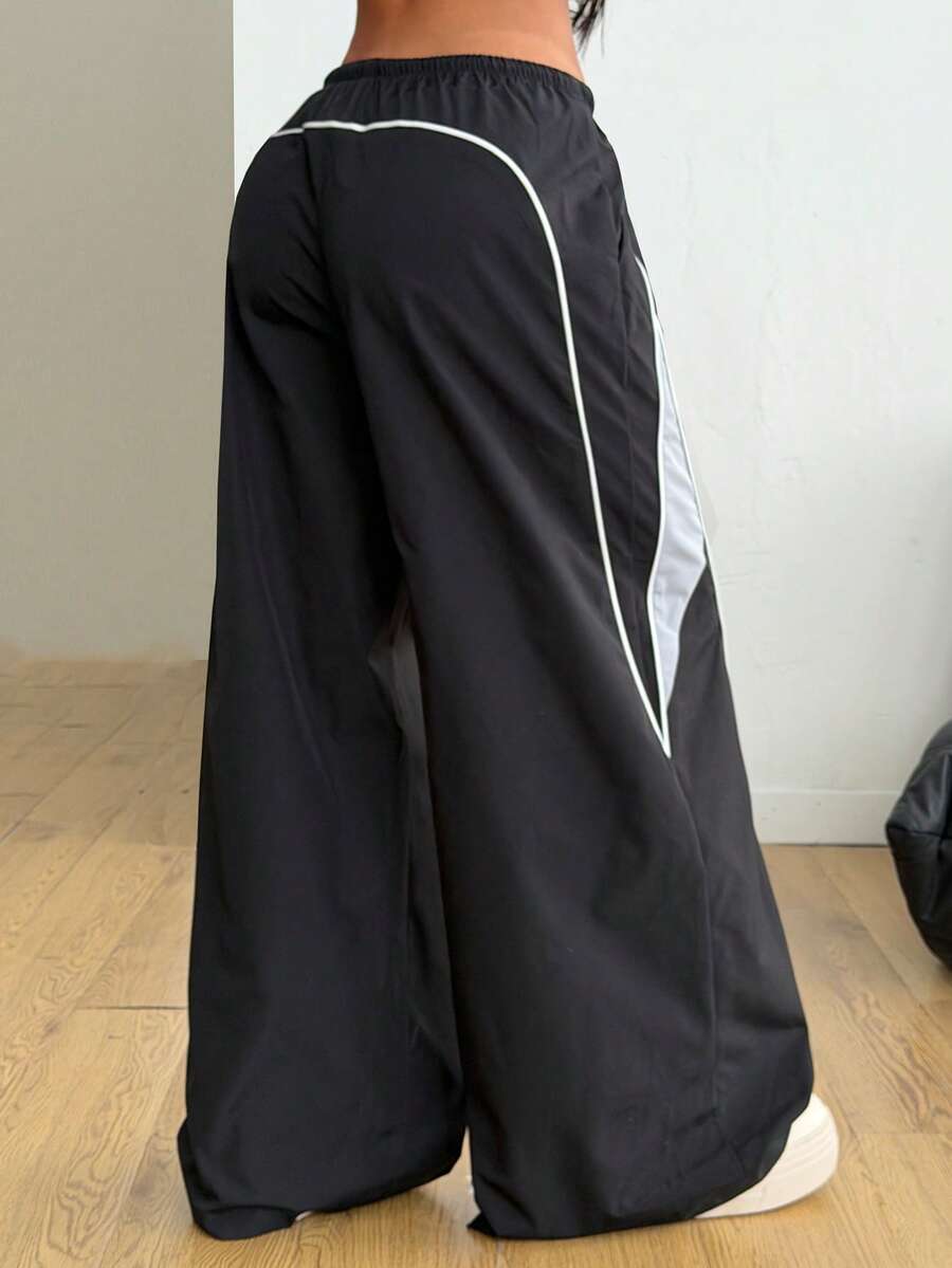 Women's wide leg parachute pants featuring an army green color-blocked design with side stripes and an adjustable drawstring waist.