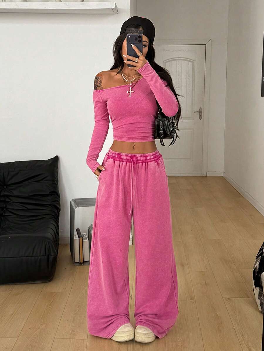 Women's two-piece knit lounge set featuring a black long sleeve asymmetrical crop top and matching high-waisted wide leg sweatpants.