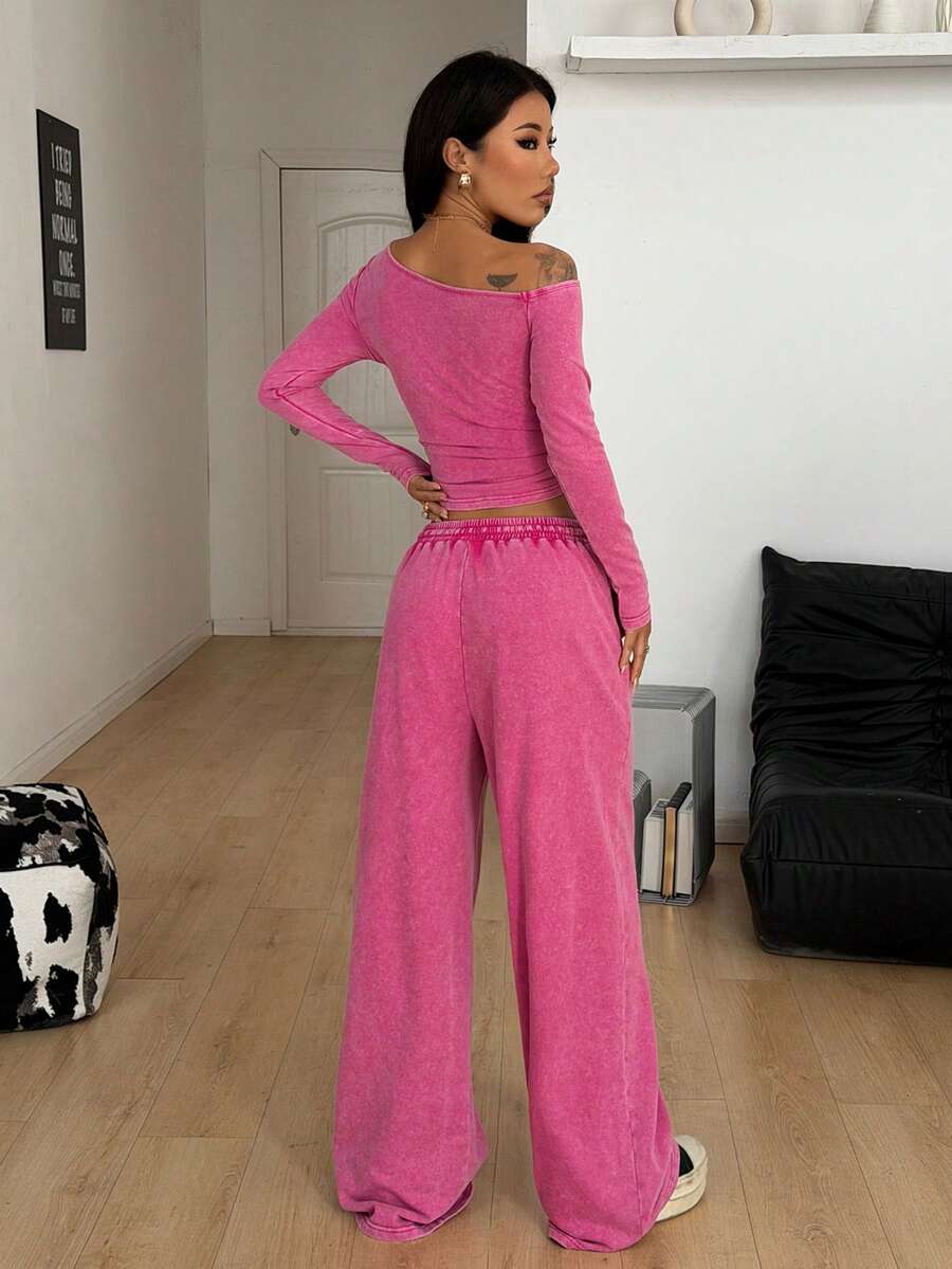 Women's two-piece knit lounge set featuring a black long sleeve asymmetrical crop top and matching high-waisted wide leg sweatpants.