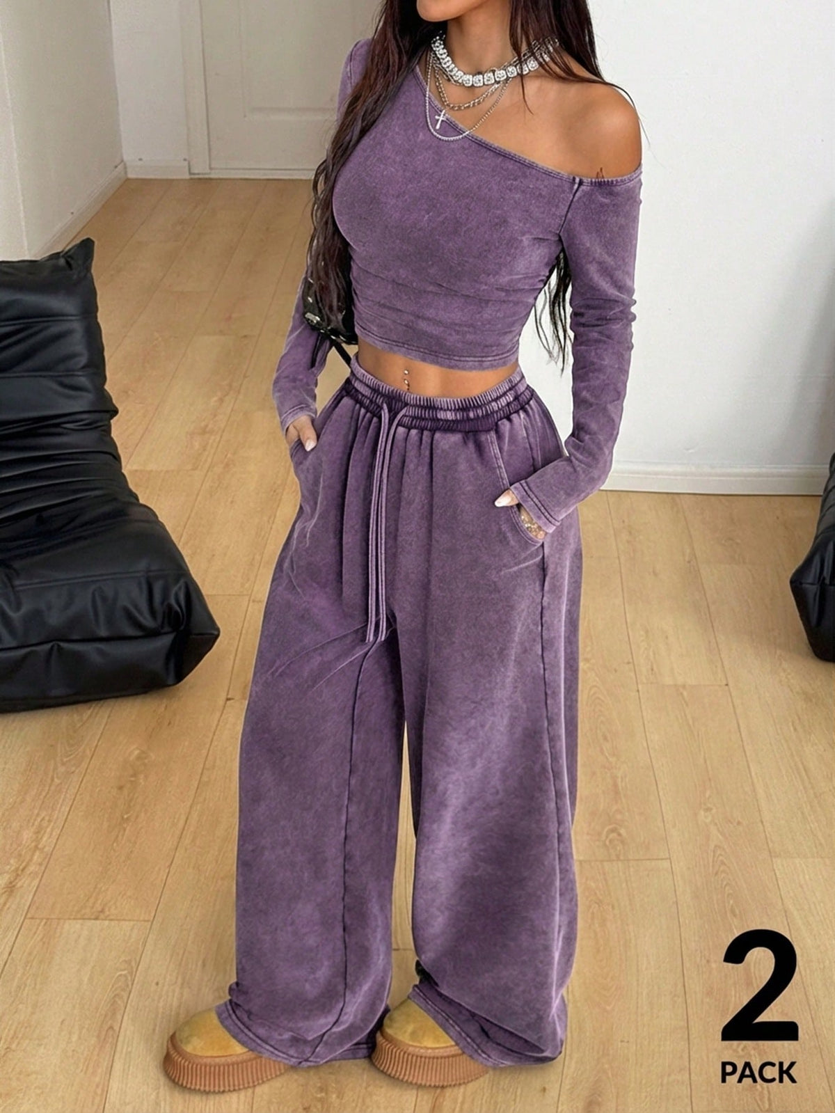 Women's two-piece knit lounge set featuring a black long sleeve asymmetrical crop top and matching high-waisted wide leg sweatpants.