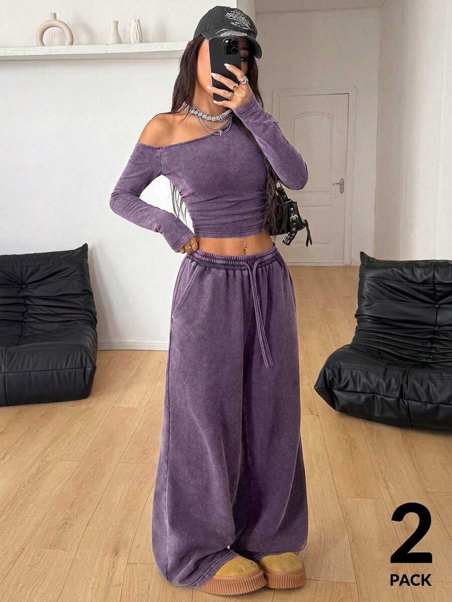 Women's two-piece knit lounge set featuring a black long sleeve asymmetrical crop top and matching high-waisted wide leg sweatpants.