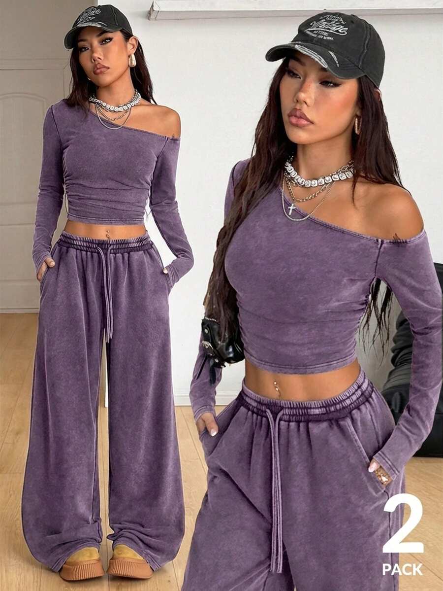 Women's two-piece knit lounge set featuring a black long sleeve asymmetrical crop top and matching high-waisted wide leg sweatpants.