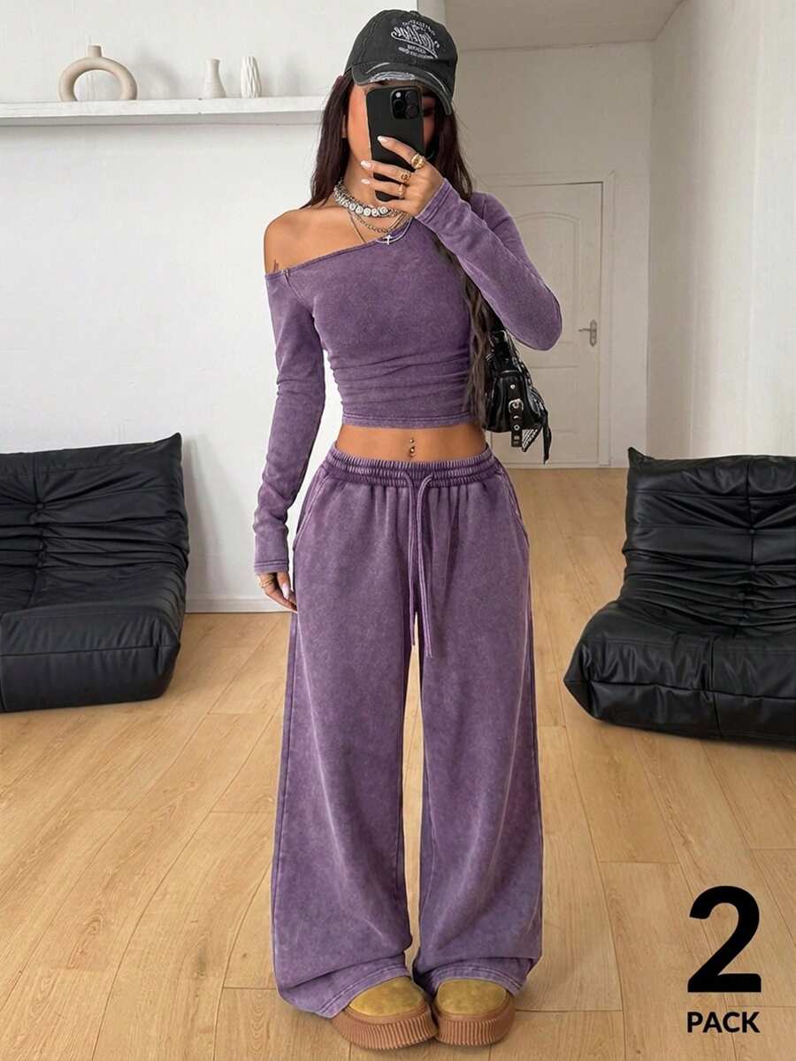 Women's two-piece knit lounge set featuring a black long sleeve asymmetrical crop top and matching high-waisted wide leg sweatpants.
