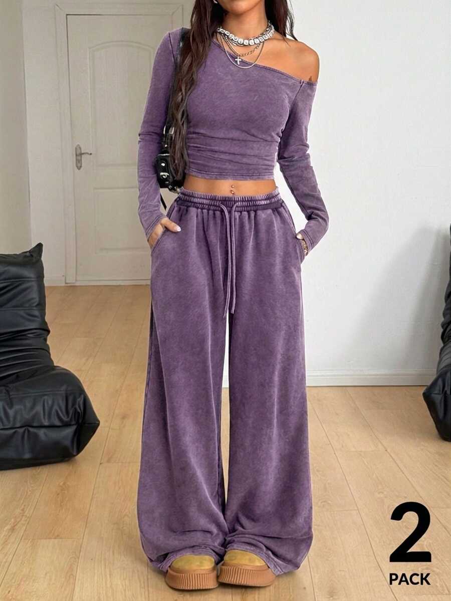 Women's two-piece knit lounge set featuring a black long sleeve asymmetrical crop top and matching high-waisted wide leg sweatpants.