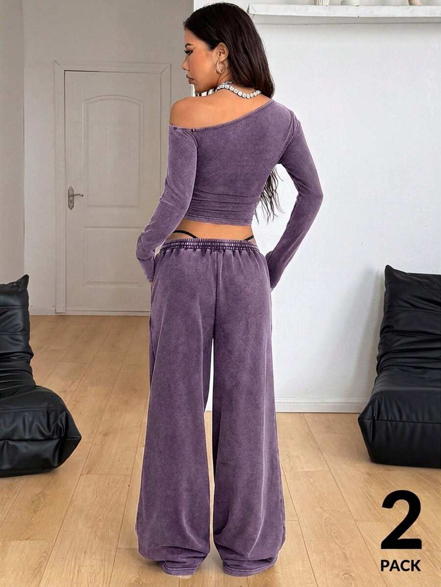 Women's two-piece knit lounge set featuring a black long sleeve asymmetrical crop top and matching high-waisted wide leg sweatpants.