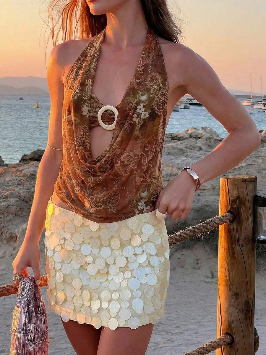 Brown and white polka dot semi-sheer halter camisole top with a plunging neckline, backless design, draped front, and metallic studded embellishments.