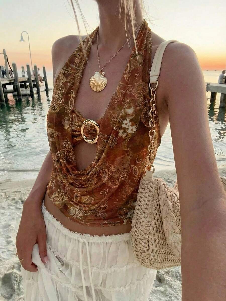 Brown and white polka dot semi-sheer halter camisole top with a plunging neckline, backless design, draped front, and metallic studded embellishments.
