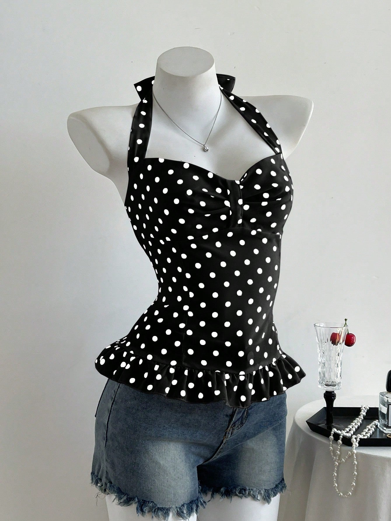 Women's polka dot halter camisole with bow bust detail, ruched and shirred design, slim crop fit, and flared ruffle hem.