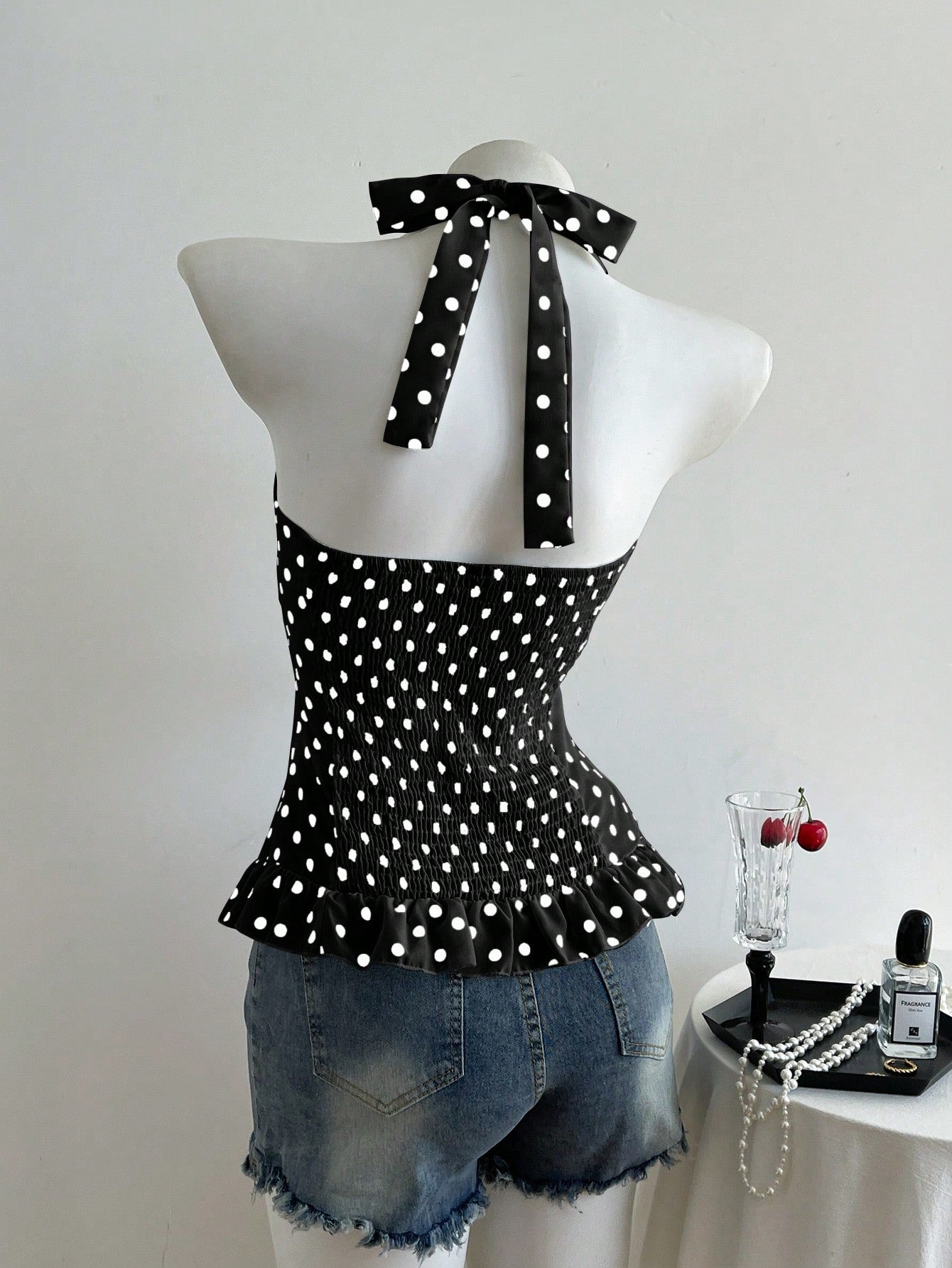 Women's polka dot halter camisole with bow bust detail, ruched and shirred design, slim crop fit, and flared ruffle hem.