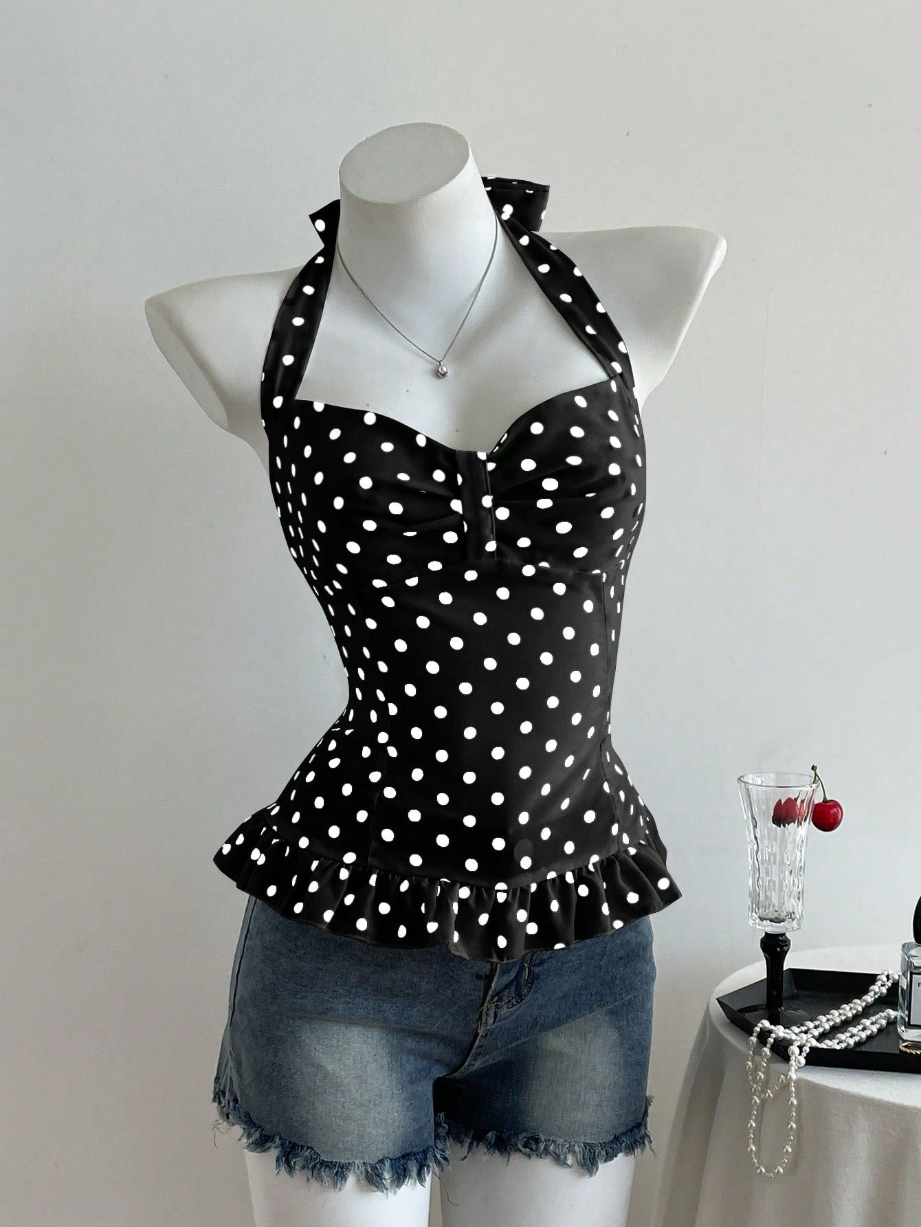 Women's polka dot halter camisole with bow bust detail, ruched and shirred design, slim crop fit, and flared ruffle hem.