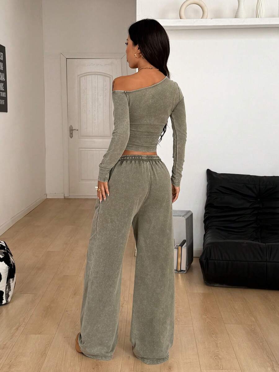 Women's two-piece knit lounge set featuring a black long sleeve asymmetrical crop top and matching high-waisted wide leg sweatpants.