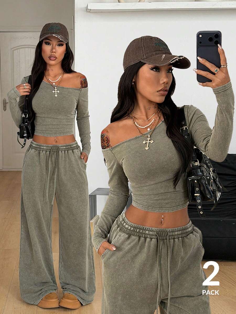Women's two-piece knit lounge set featuring a black long sleeve asymmetrical crop top and matching high-waisted wide leg sweatpants.