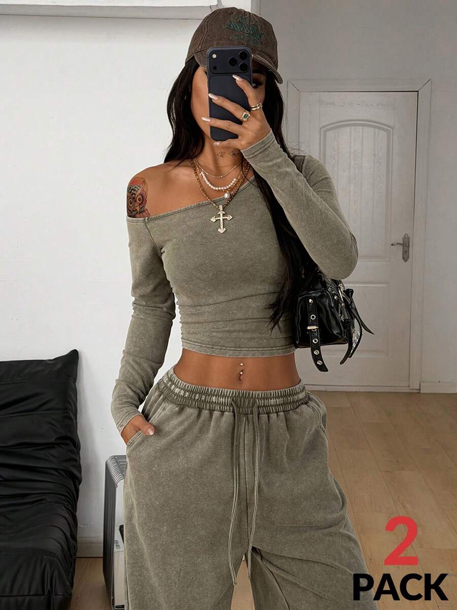 Women's two-piece knit lounge set featuring a black long sleeve asymmetrical crop top and matching high-waisted wide leg sweatpants.