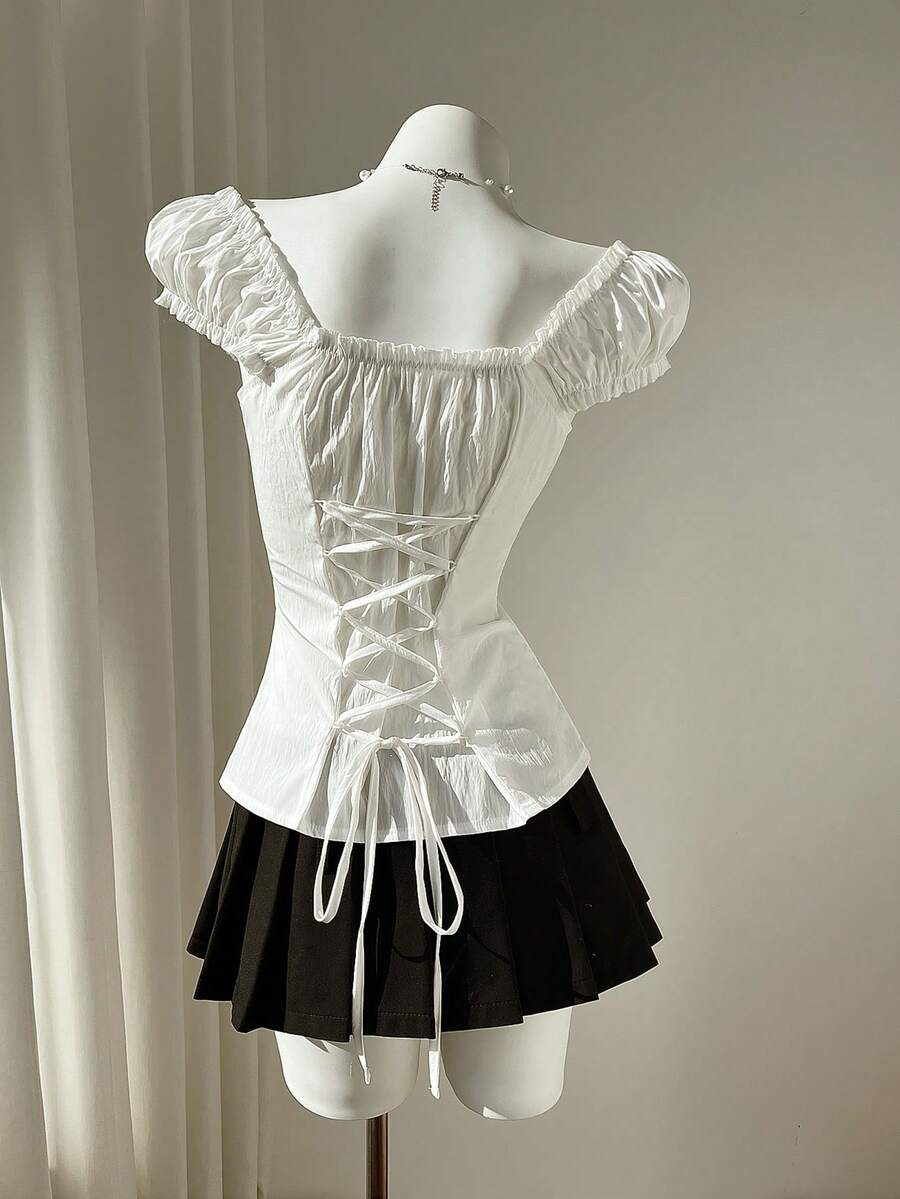 Women's black off-shoulder cap sleeve blouse with ruffled detailing and a tie-back design.