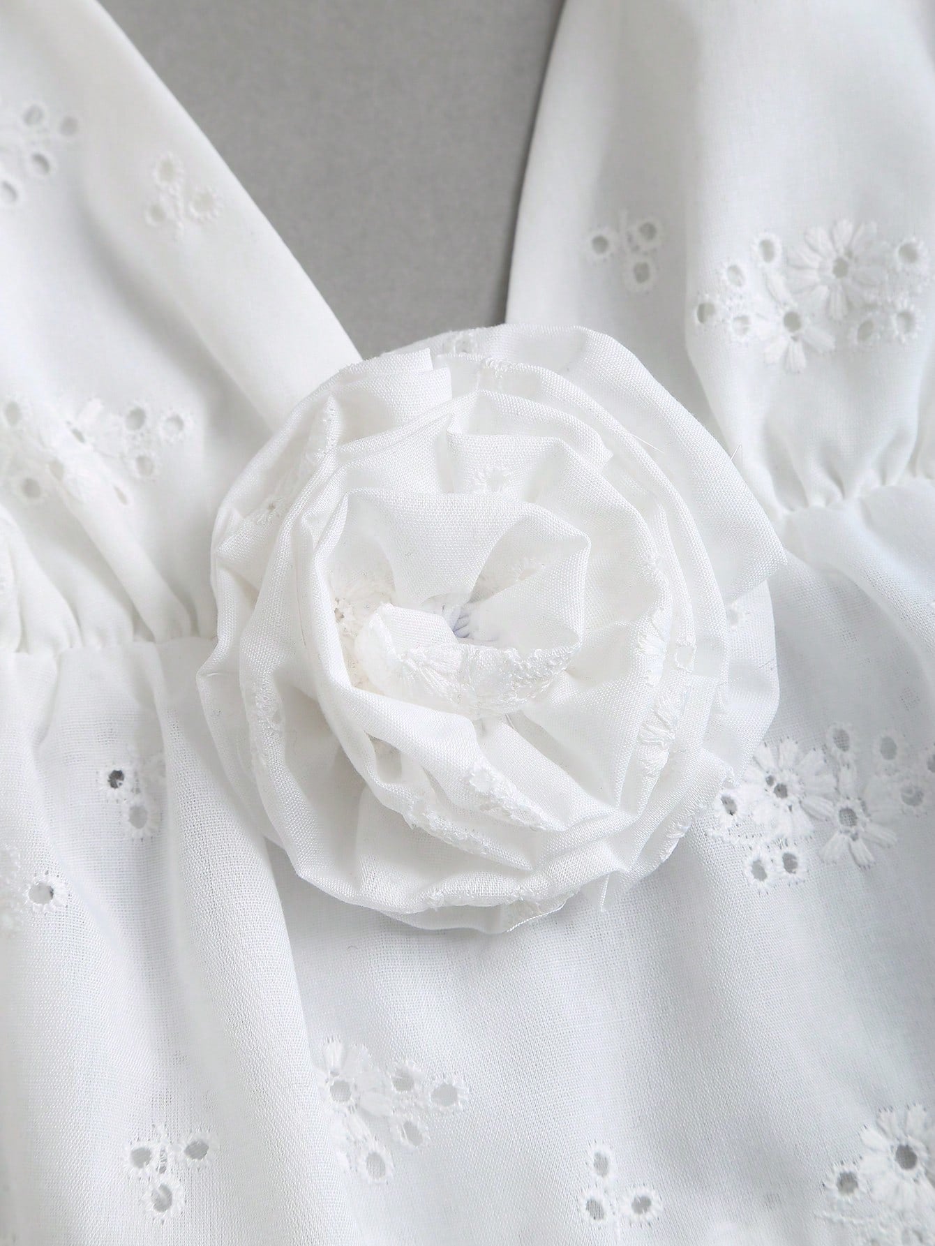 Women's white spaghetti strap cami top with eyelet embroidery, knot detail, ruffle hem, and flared hem shape