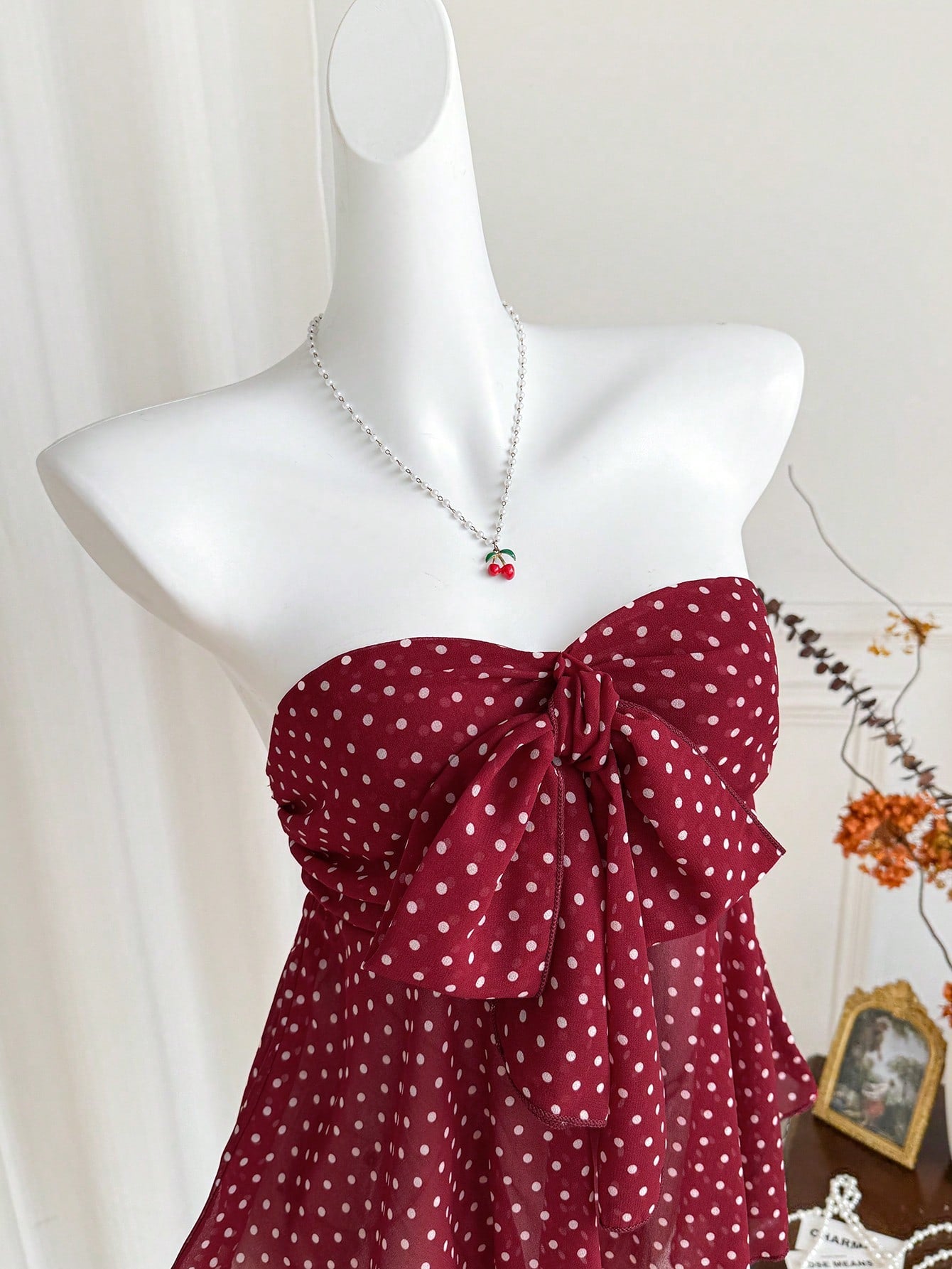 Women's polka dot strapless bandeau crop top with tie bow detail, asymmetrical shirring, and a flared hem.