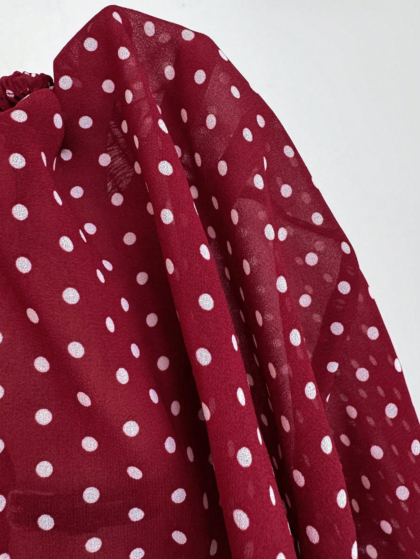 Women's polka dot strapless bandeau crop top with tie bow detail, asymmetrical shirring, and a flared hem.