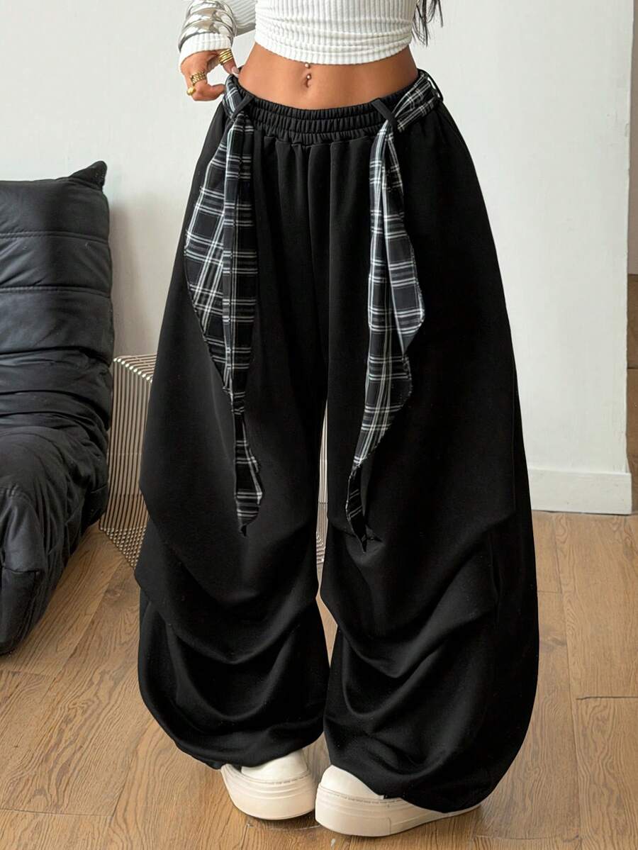 Loose-fitting black baggy parachute pants featuring an elastic drawstring waistband and wide-leg cut made from cotton blend fabric.